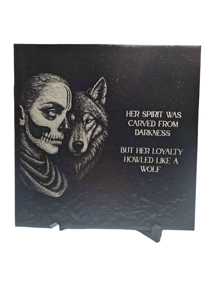 Decorative plaque with a skull and wolf design on a stand.
