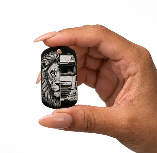 A hand with manicured nails holds a small tire-shaped keychain or tag against a plain white background. The tag features a printed graphic of a black and gray tire with a silver rim and a black loop at the top.